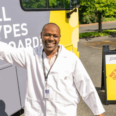 A blood collection specialist welcomes you onto our newest bloodmobile